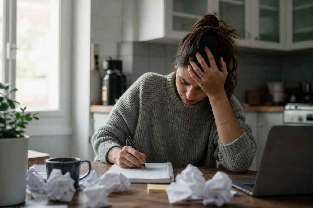 Overwhelmed person doing a brain dump in a notebook at home